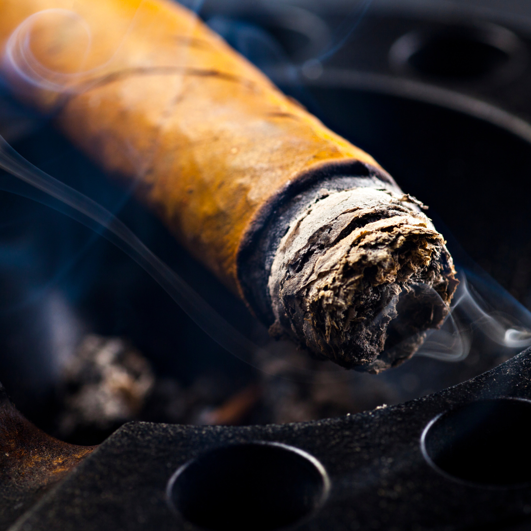 Close-up of a smoking cigar on a black ashtray